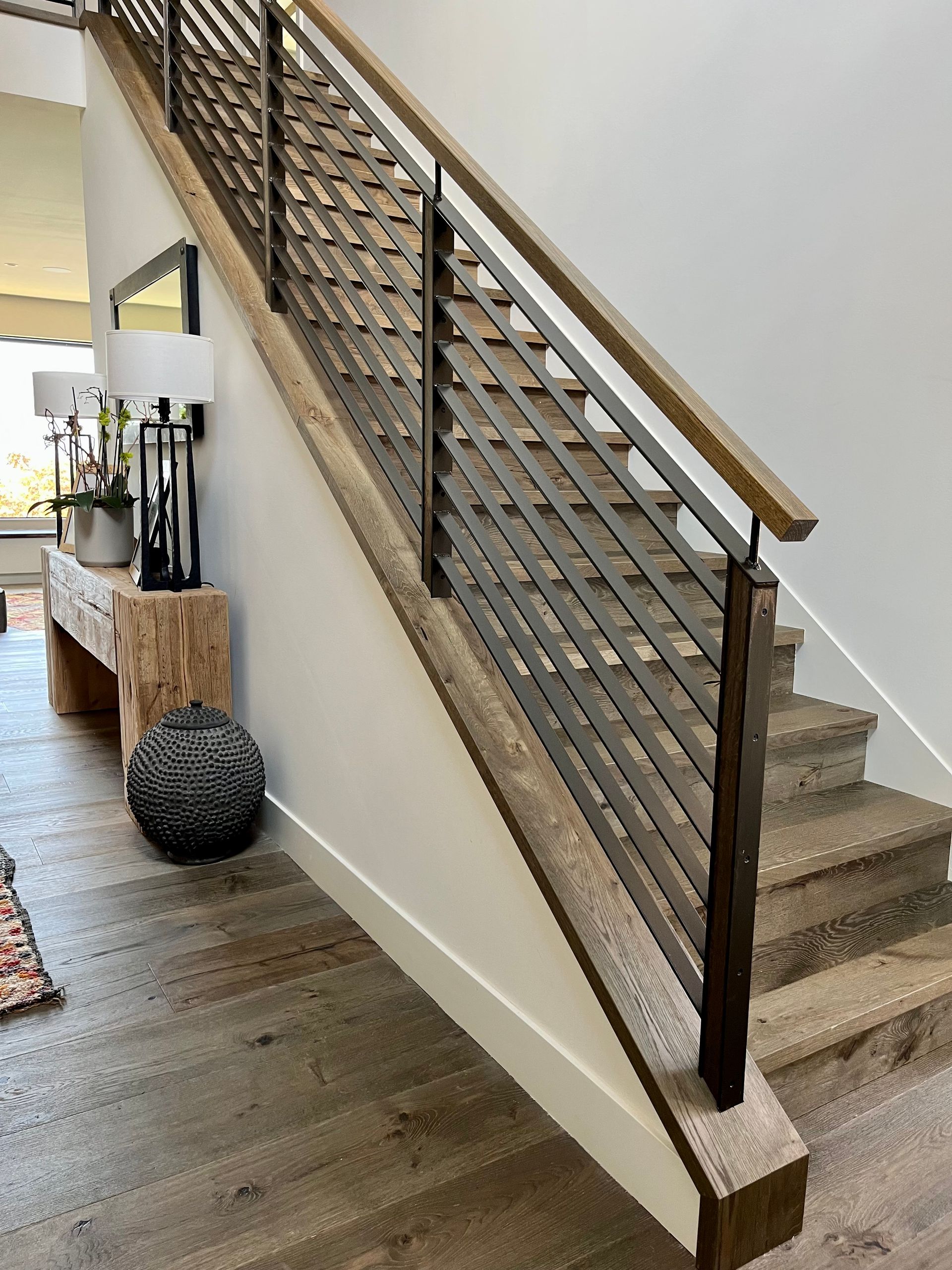 A wooden staircase with a metal railing in a living room.