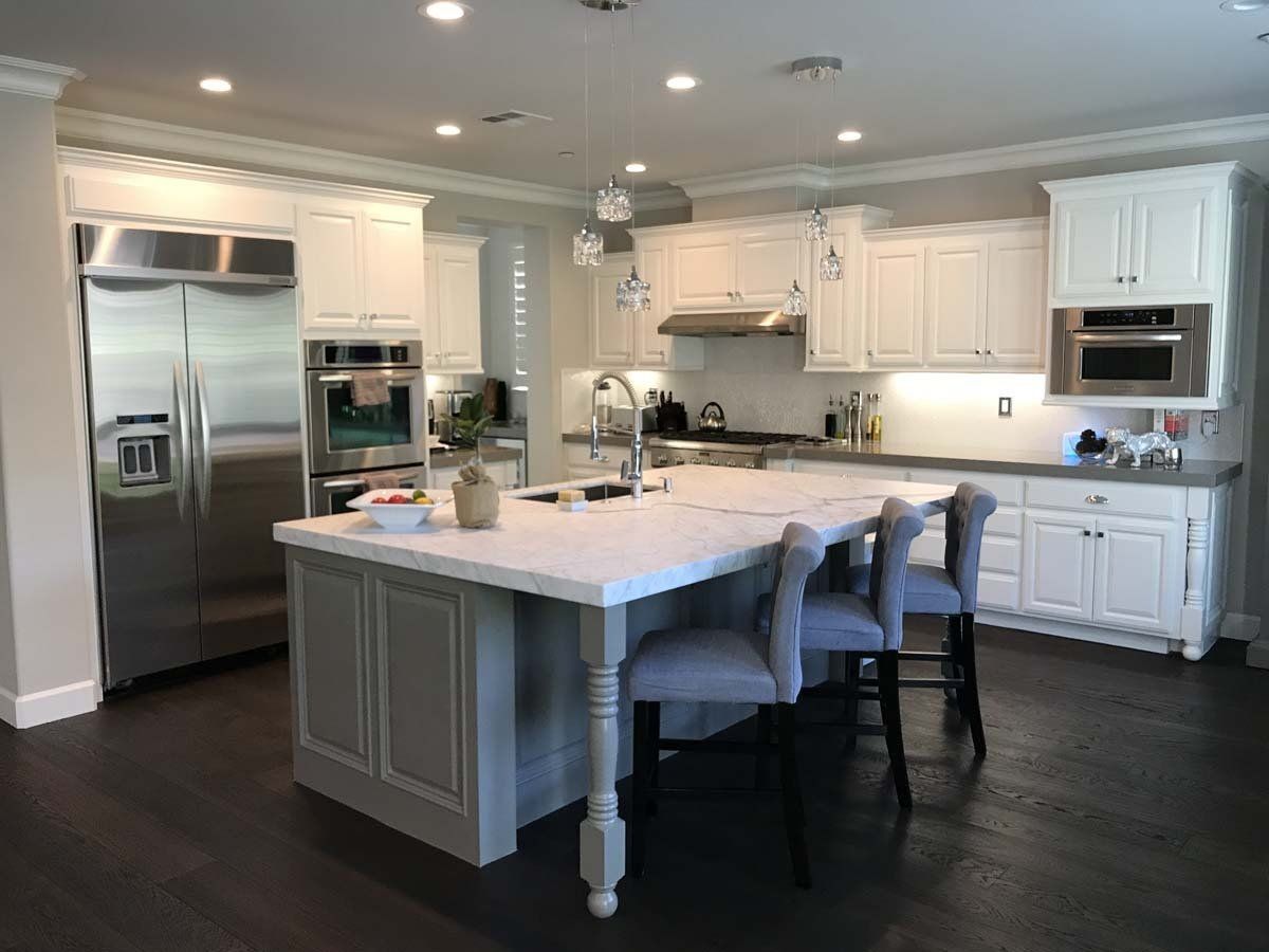 A kitchen with white cabinets , stainless steel appliances , and a large island.