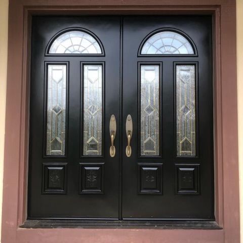 A black double door with stained glass windows and gold handles