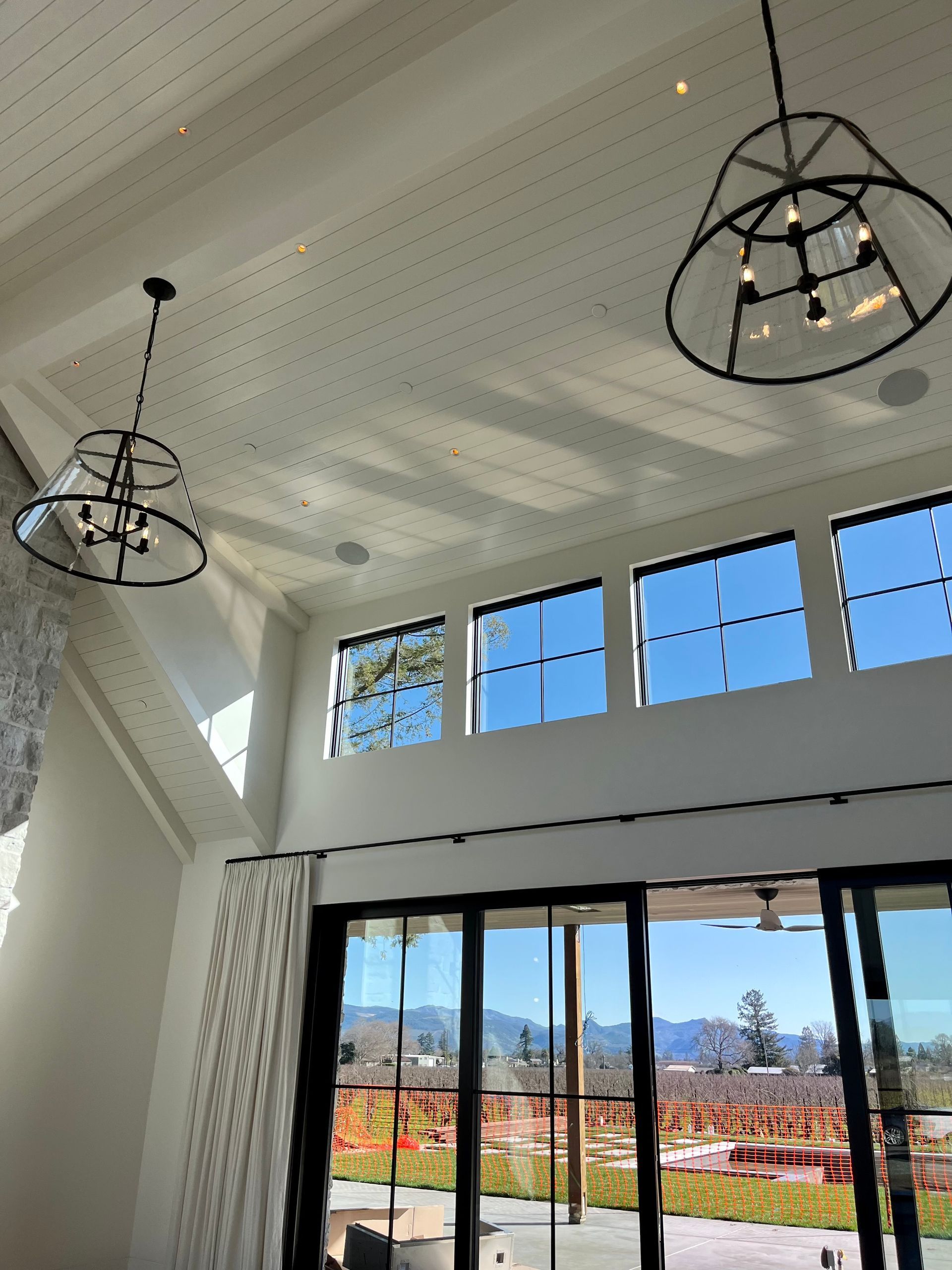 A living room with a lot of windows and a chandelier hanging from the ceiling