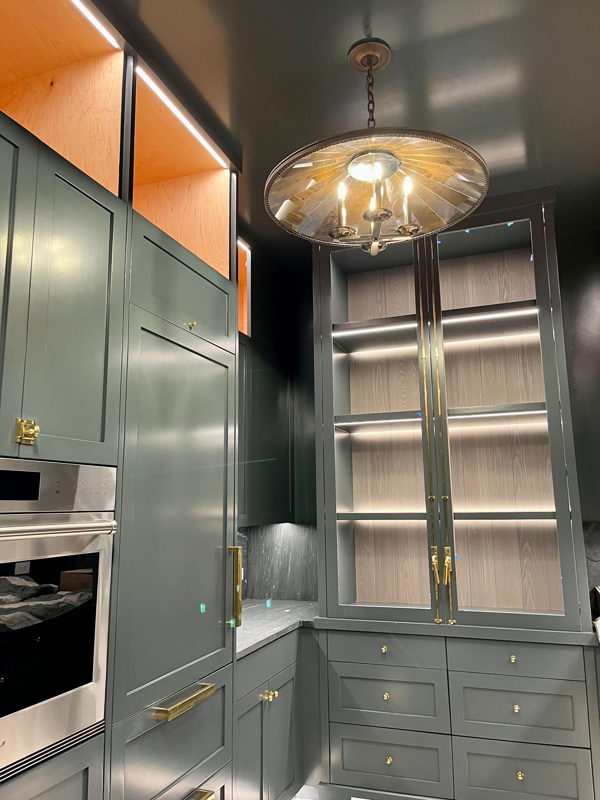 A kitchen with green cabinets and a chandelier hanging from the ceiling.