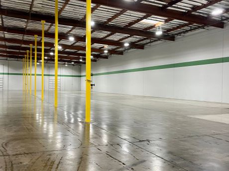 an empty warehouse with yellow poles and green stripes on the walls