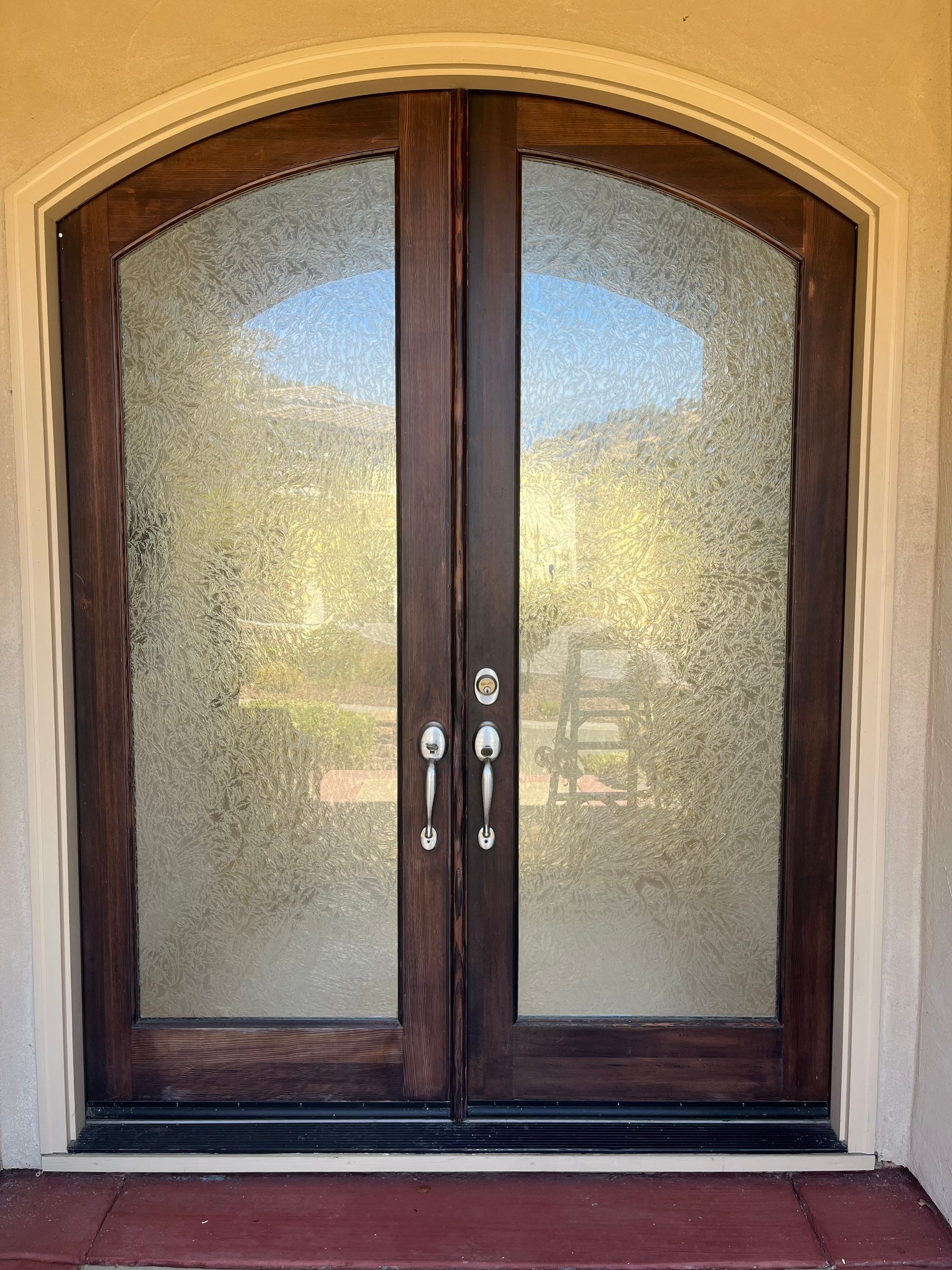 A pair of arched wooden doors with frosted glass.