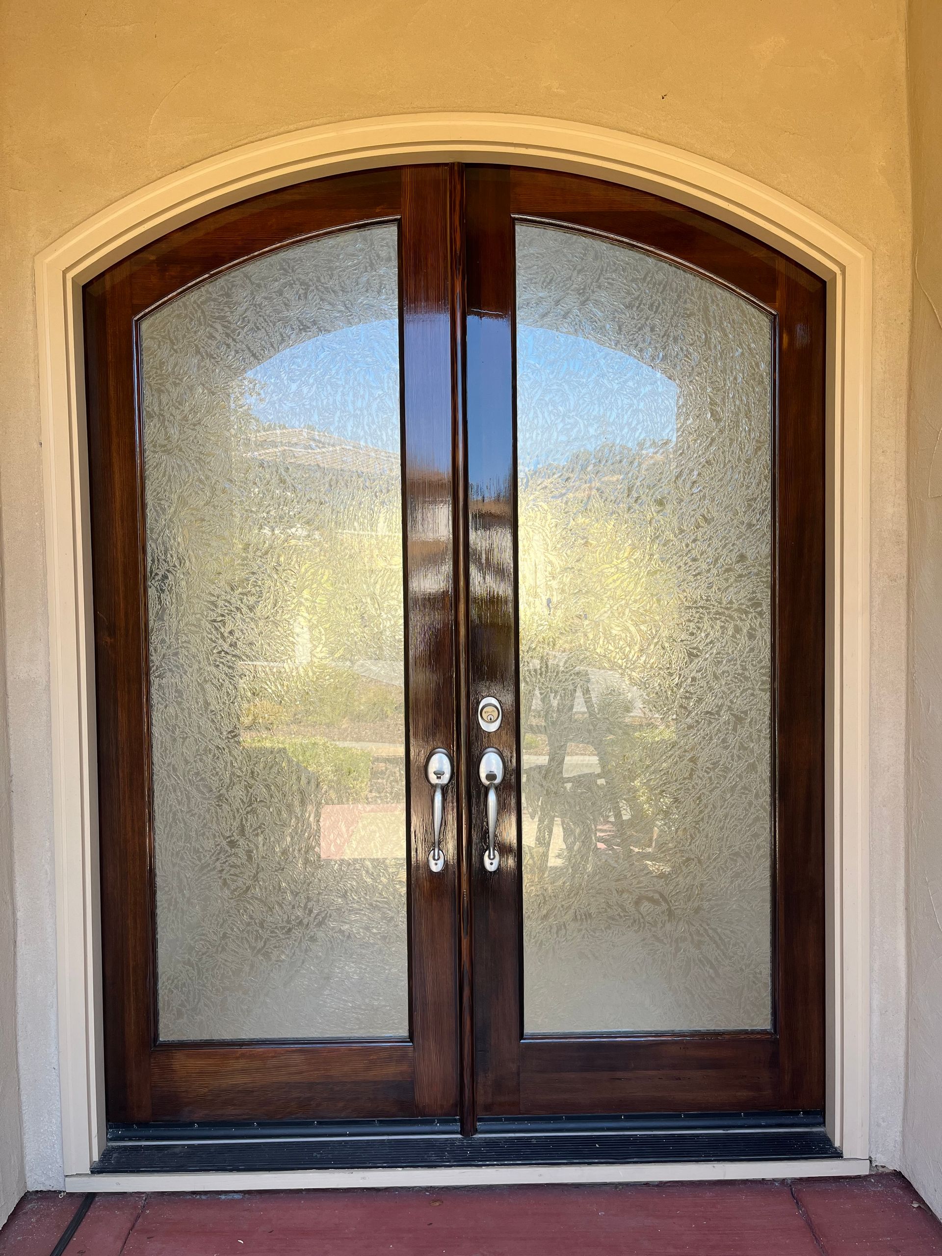 A pair of arched wooden doors with stained glass in a house.