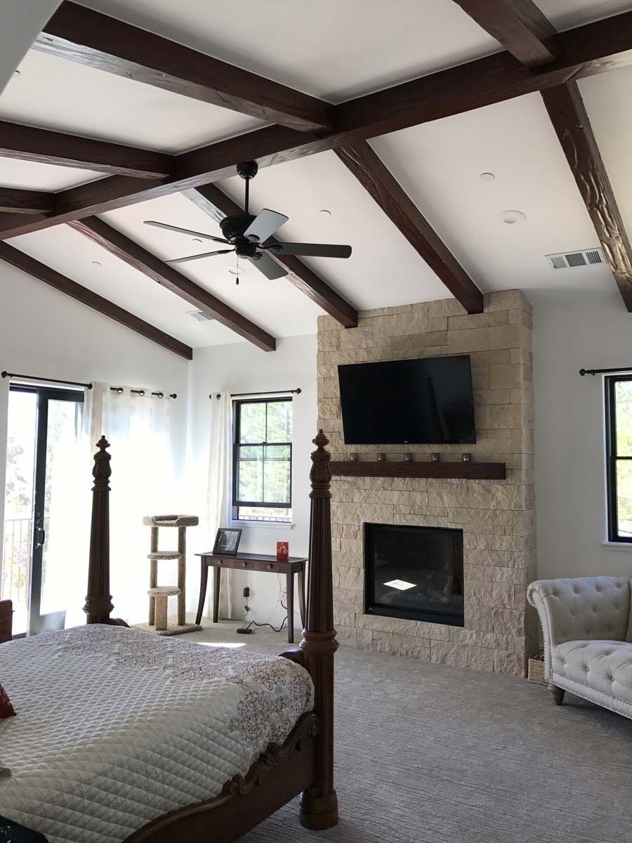 A bedroom with a fireplace and a ceiling fan