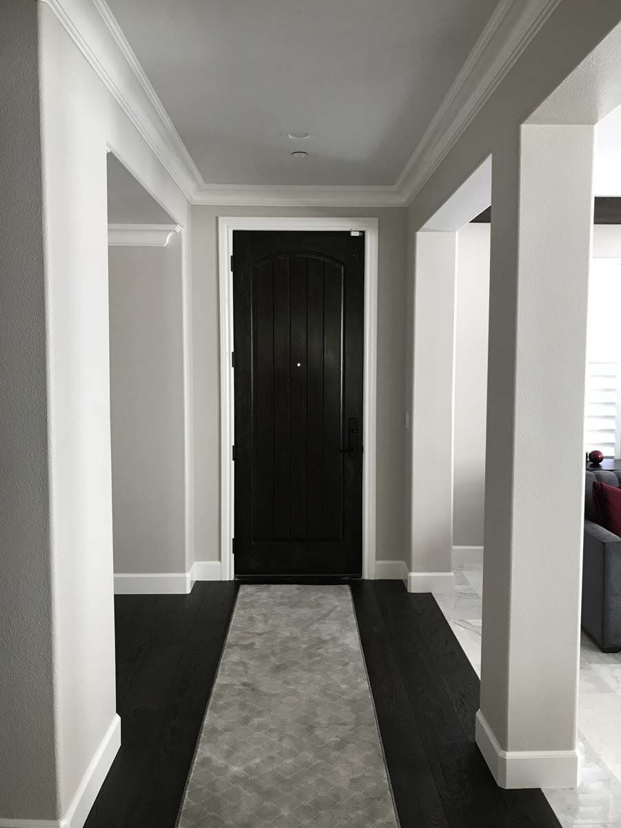 A hallway with a black door and a white rug