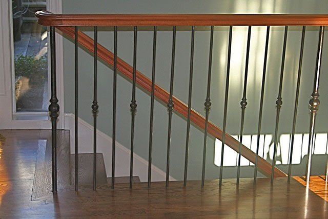 A staircase with a wrought iron railing and a wooden handrail.