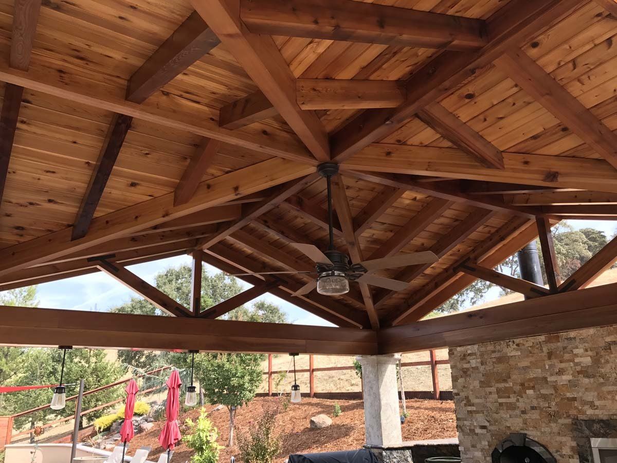 A ceiling fan is hanging from the ceiling of a wooden structure.
