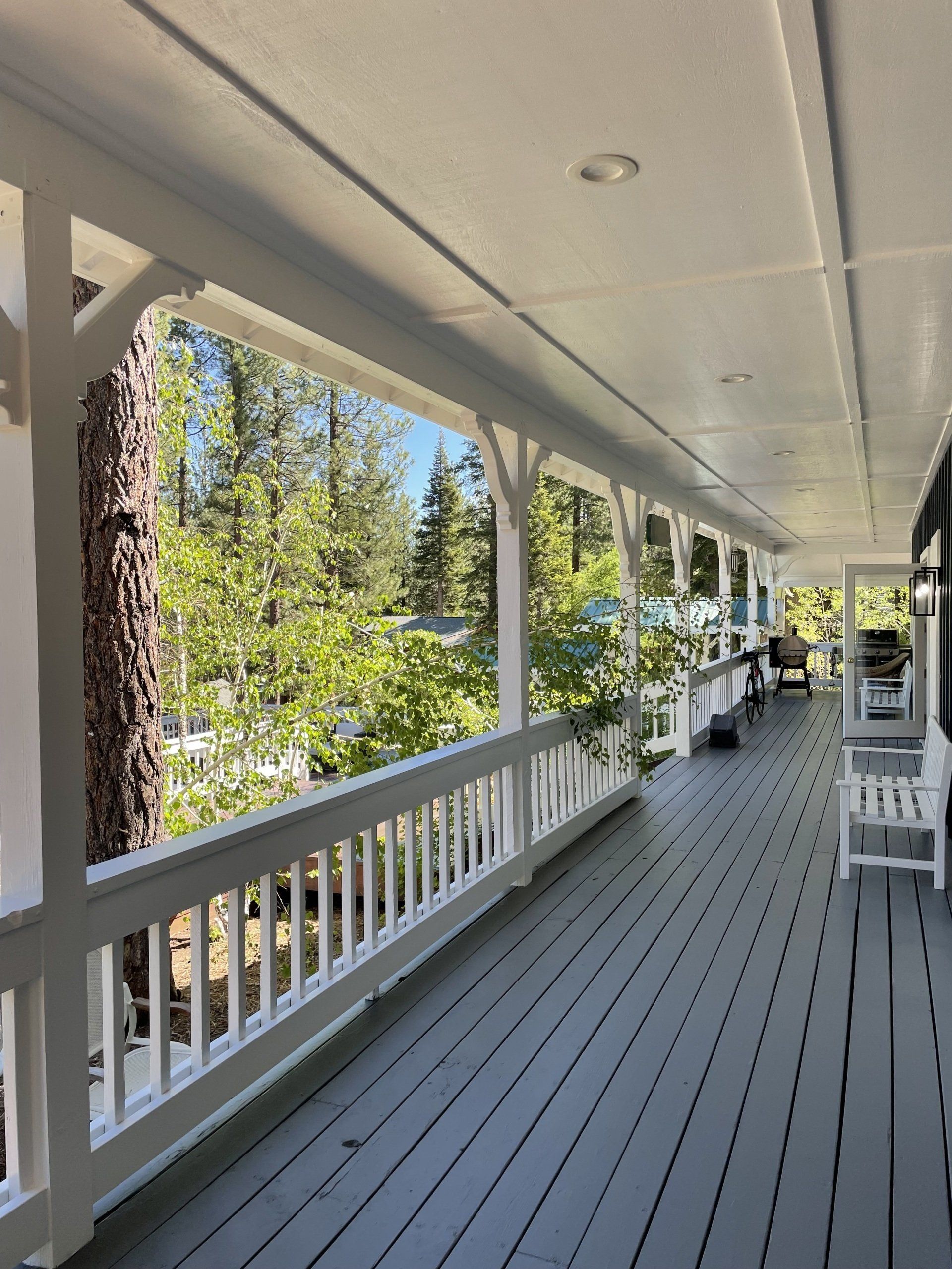 A long porch with a white railing and chairs