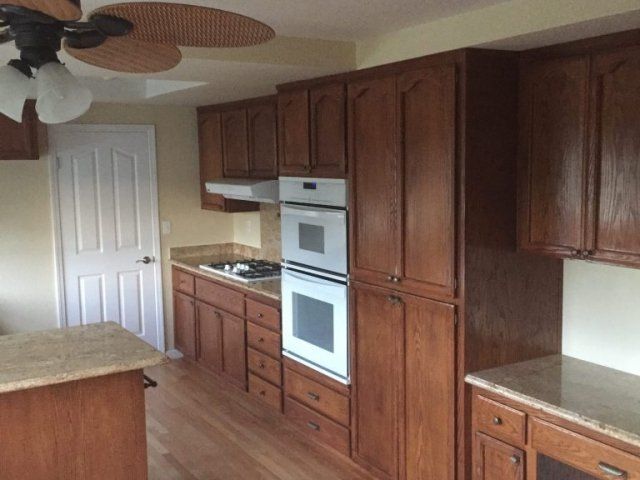 A kitchen with wooden cabinets and a ceiling fan