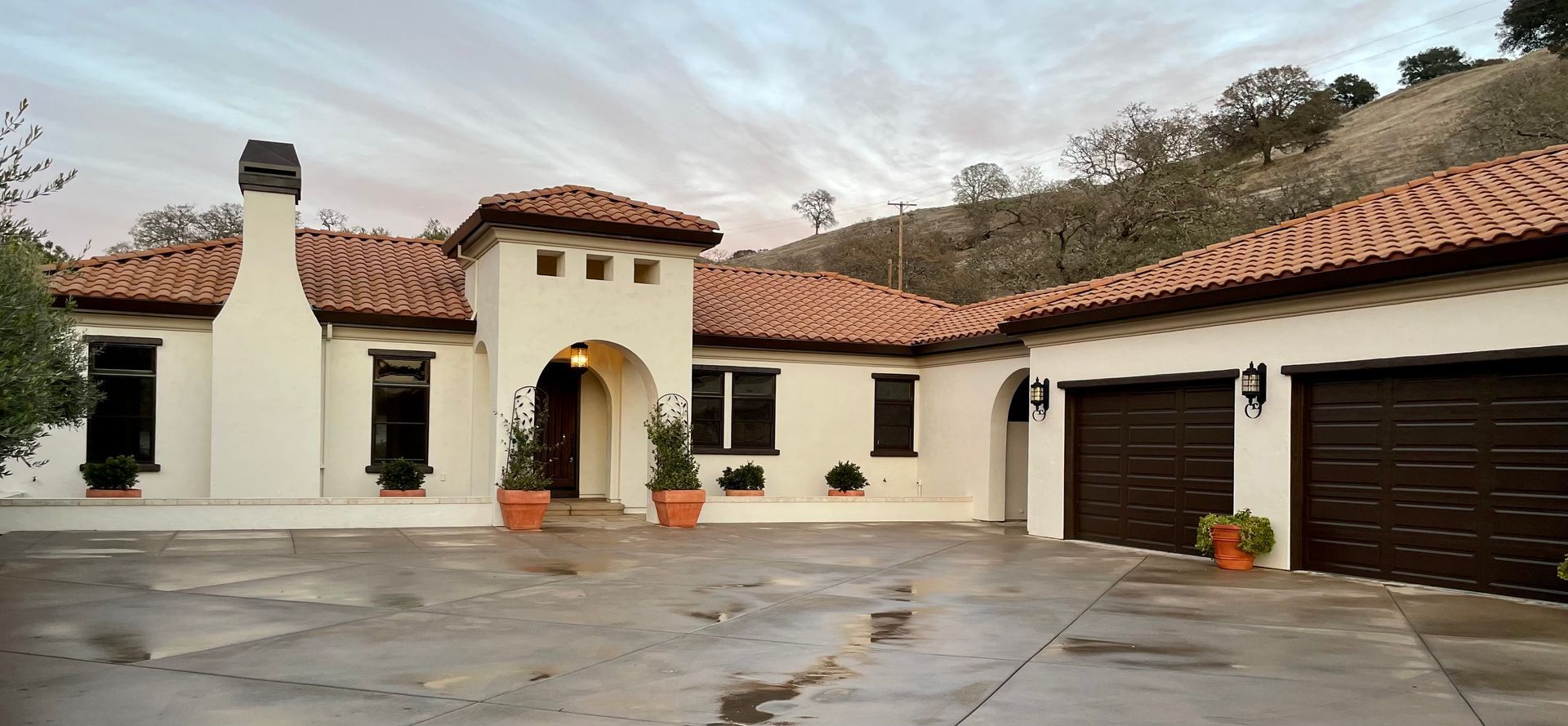 A large white house with brown garage doors and a tiled roof