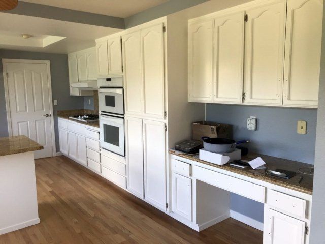 A kitchen with white cabinets and hardwood floors
