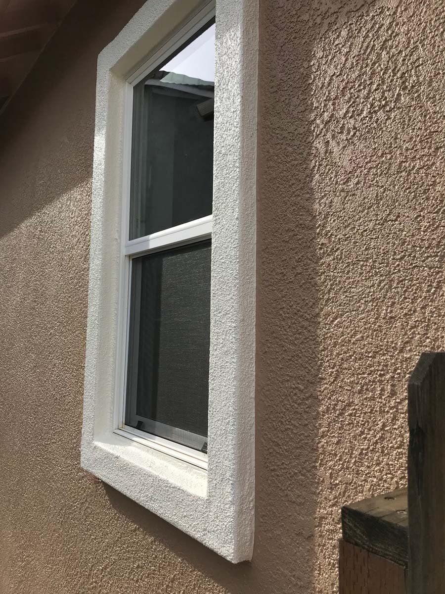 A window on the side of a house with a white frame.