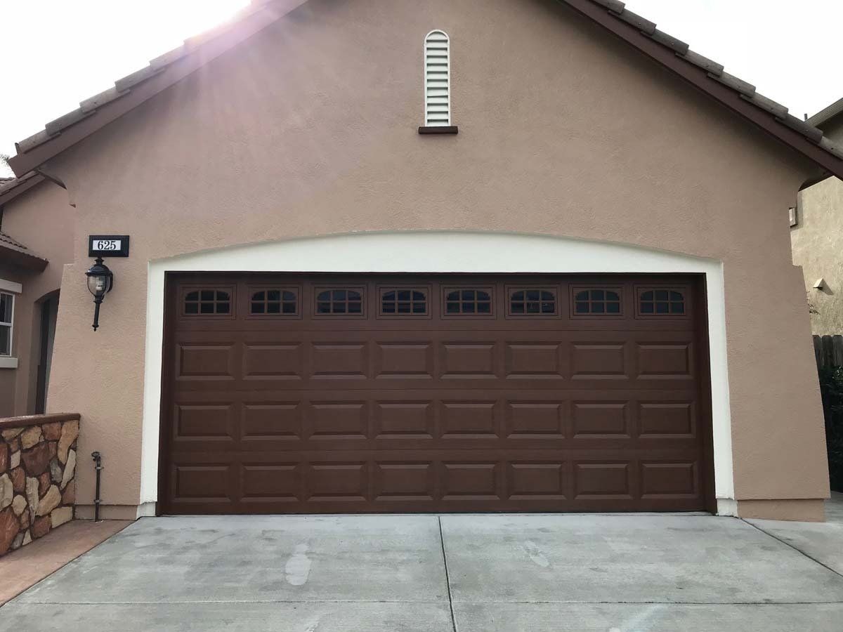A large brown garage door is on the side of a house