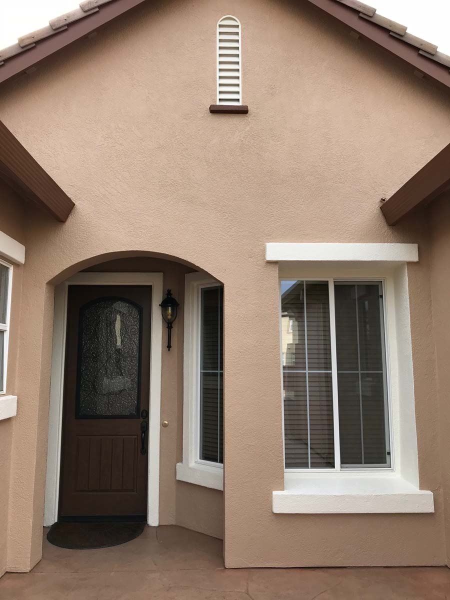 The front of a house with a brown door and white windows