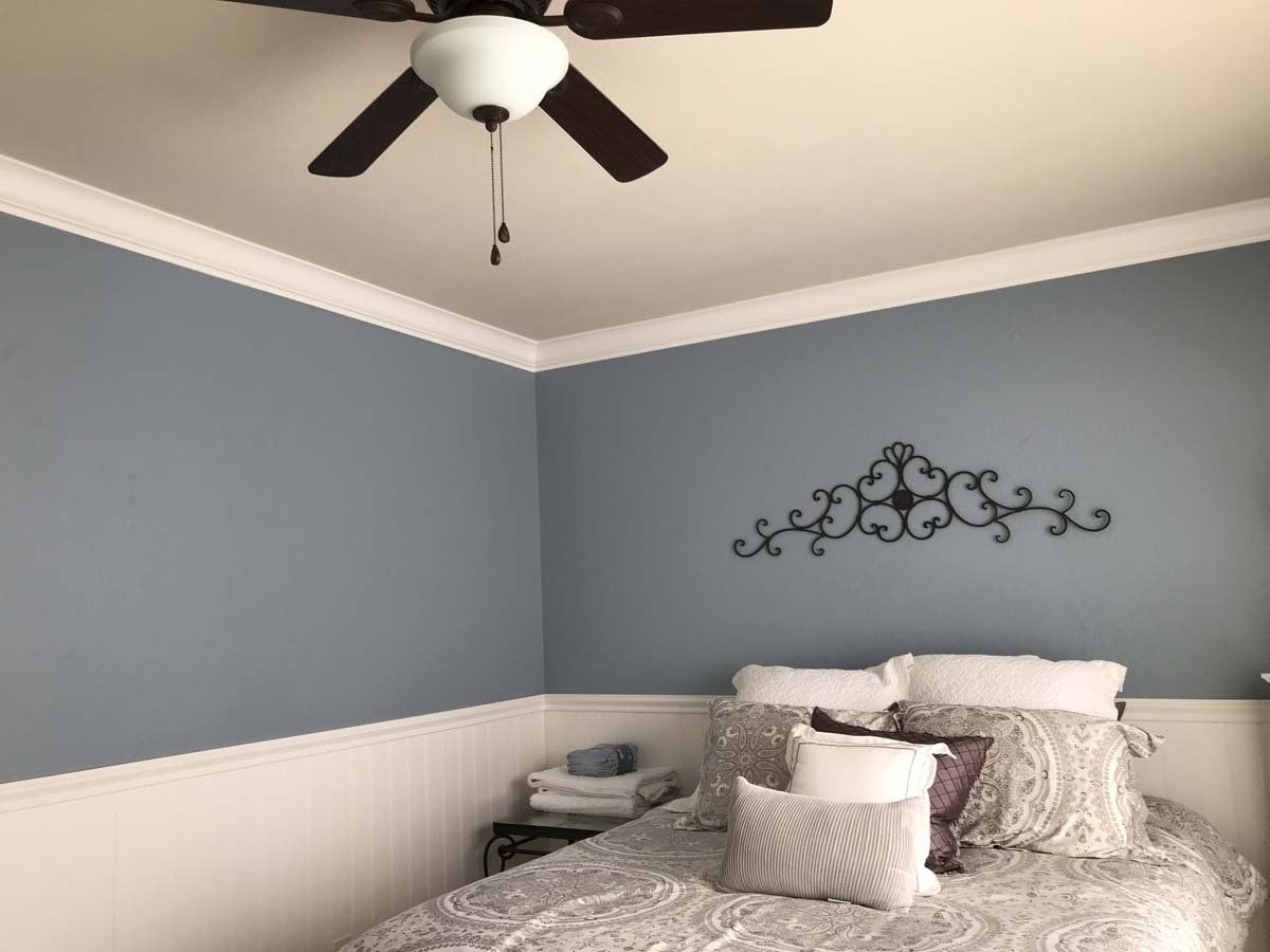 A bedroom with a bed and a ceiling fan