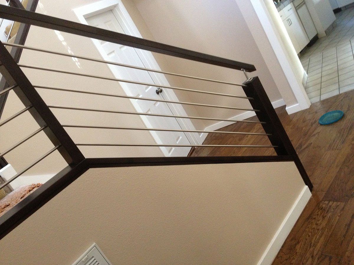 A staircase with a stainless steel railing and a wooden handrail