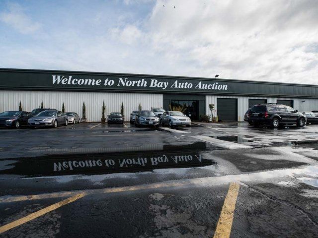 Cars are parked in front of a building that says welcome to north bay auto auction