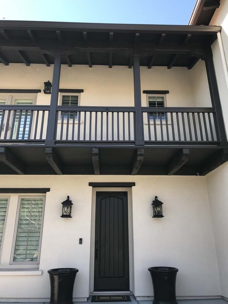 A white house with a black door and balcony