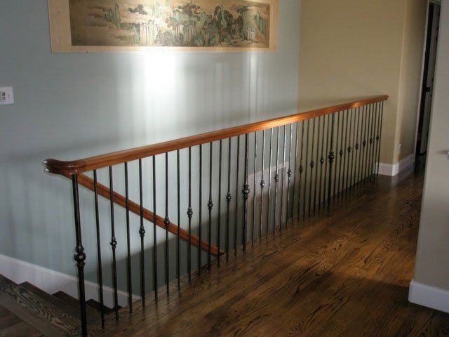 A staircase with a wrought iron railing and a wooden handrail
