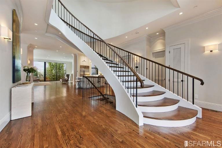 A white staircase with wooden steps and a black railing in a house.
