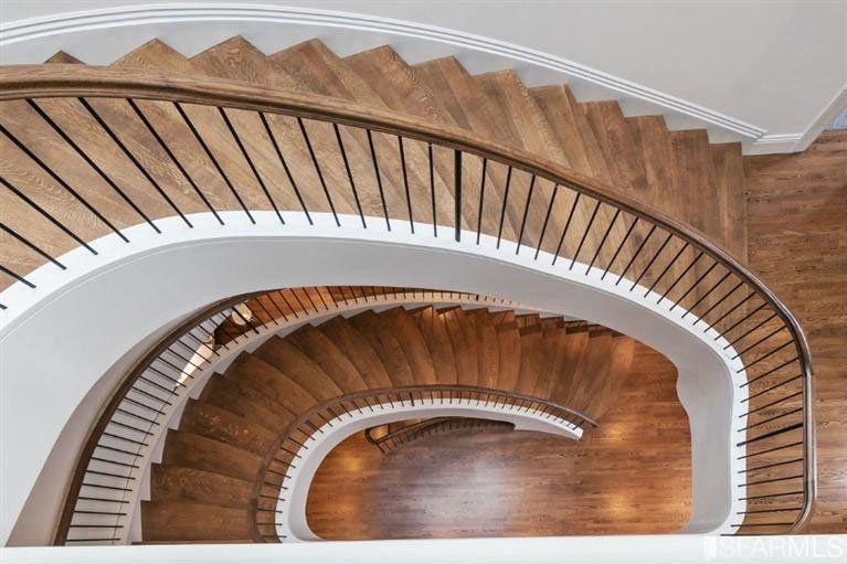 A spiral staircase with wooden steps and a white railing