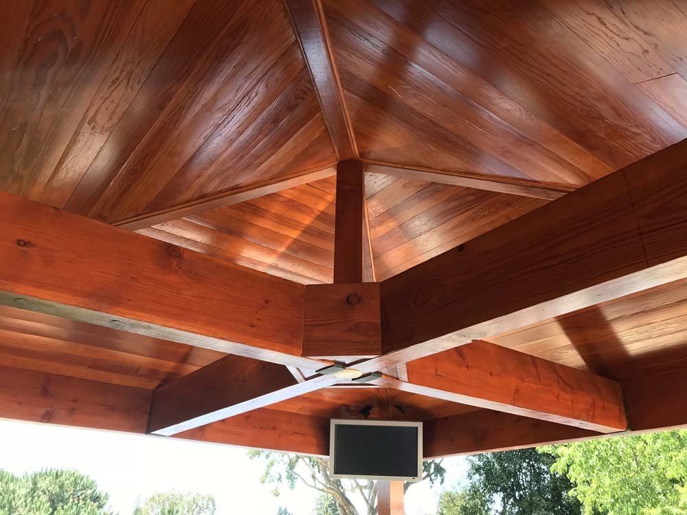 A wooden gazebo with a tv mounted to the ceiling