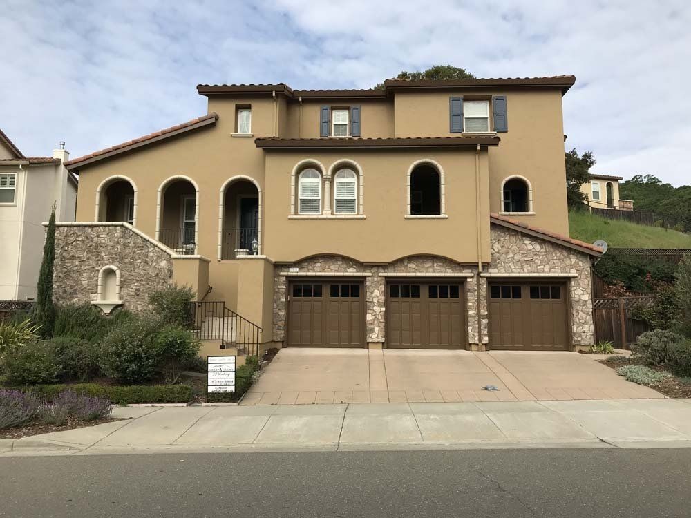 A large house with three garage doors and arched windows
