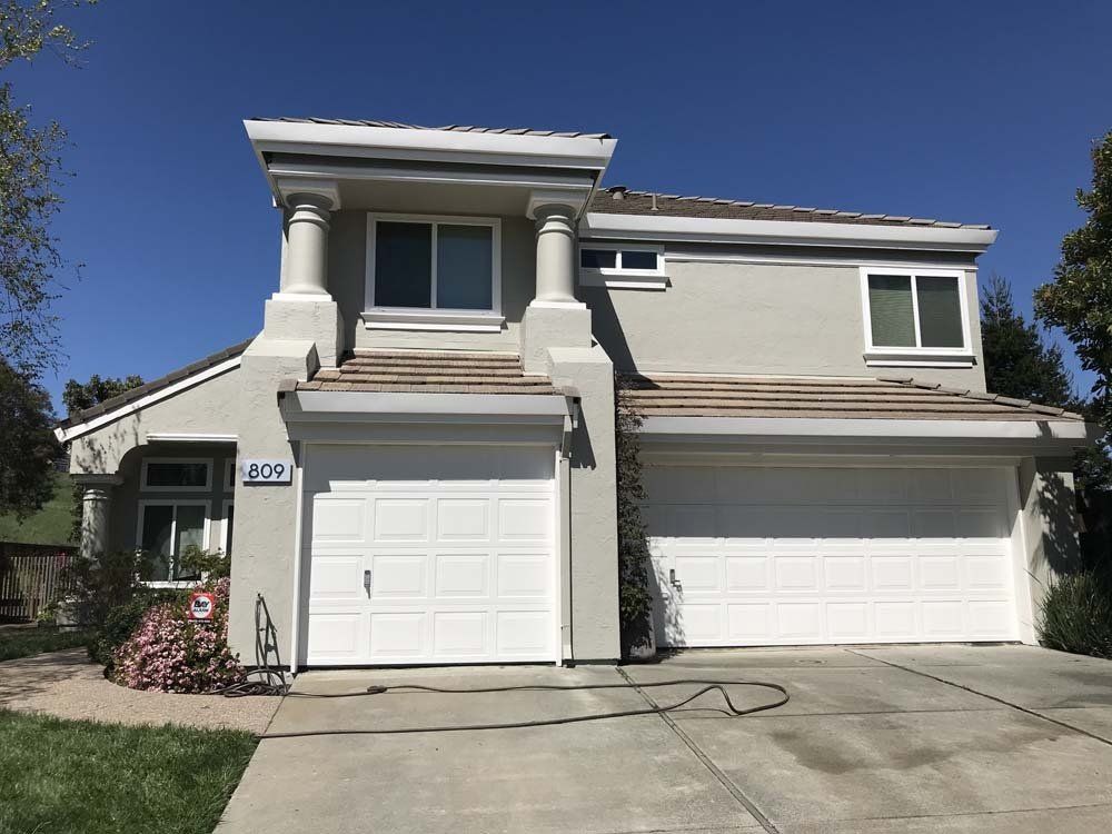 A large house with a white garage door and a blue sky in the background.