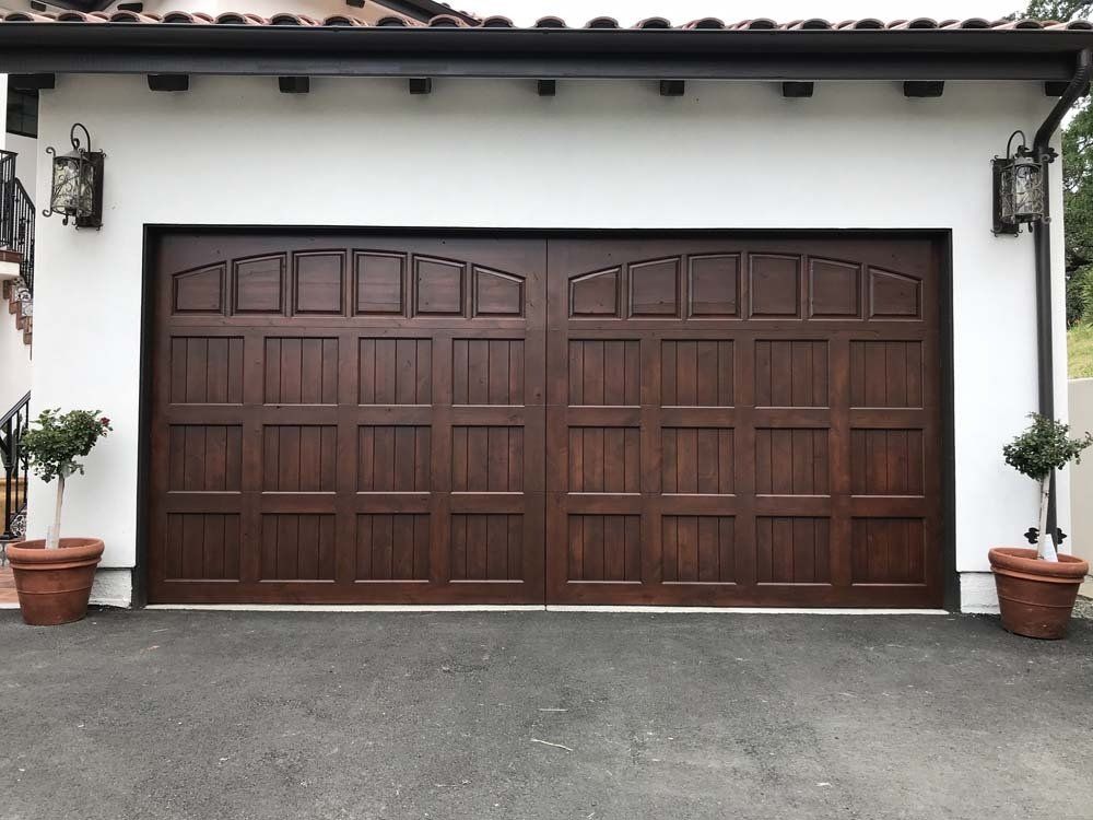 A wooden garage door with a white wall behind it