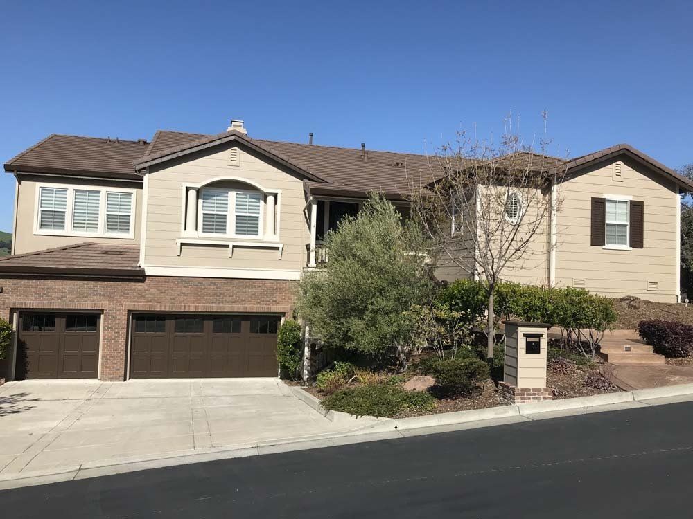 A large house with two garage doors is sitting on top of a hill.