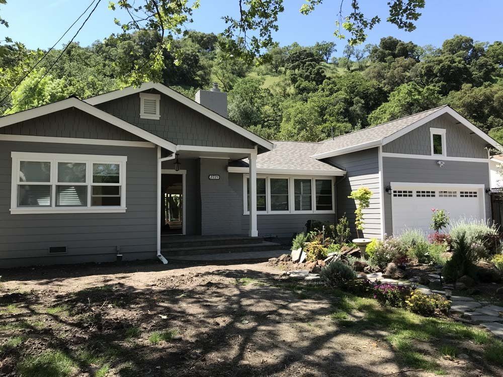 A gray house with white trim and a white garage door