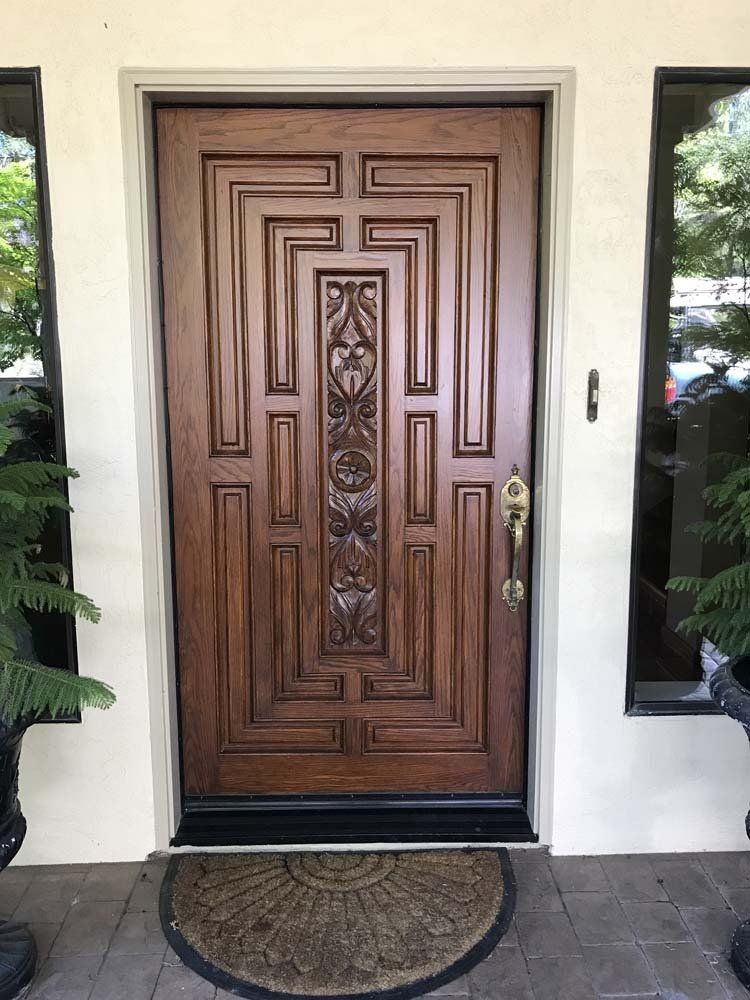 A wooden door with a rug in front of it on a porch.