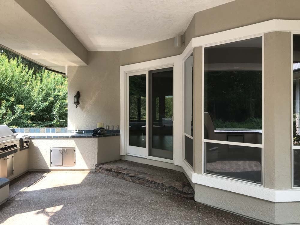 A large screened in porch with sliding glass doors and a grill.