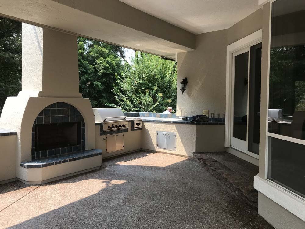 A patio with a fireplace and a grill on it