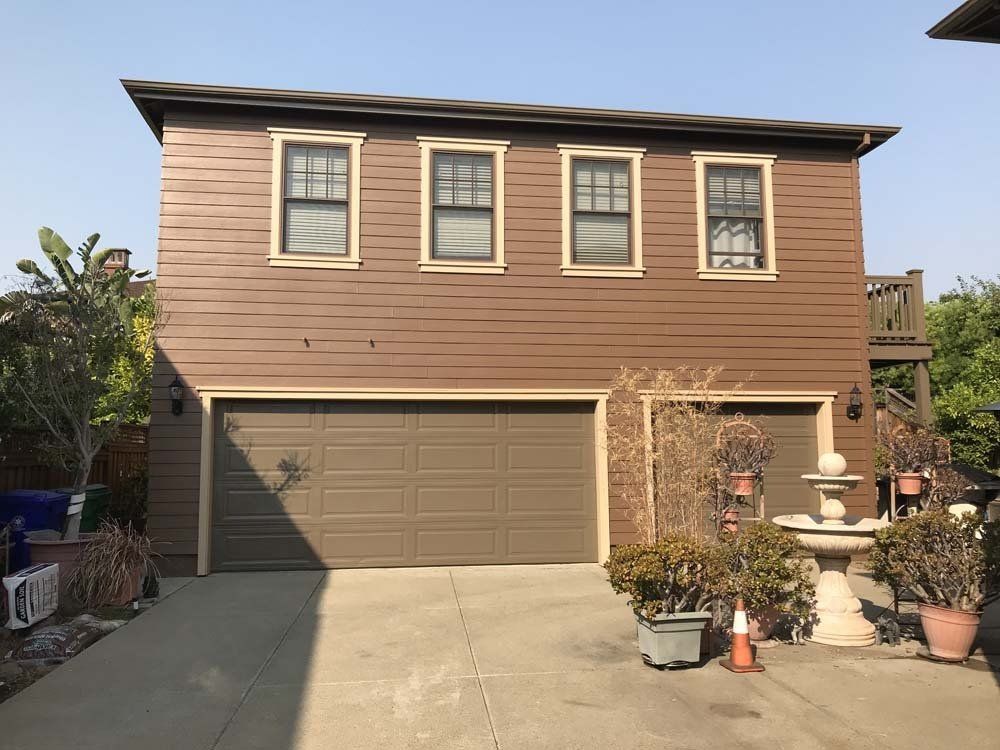 A brown house with a garage and a lot of windows
