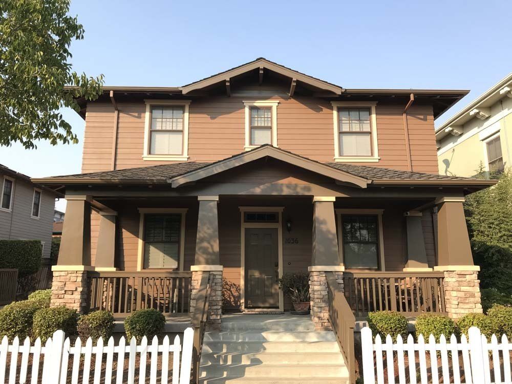 A brown house with a white picket fence in front of it