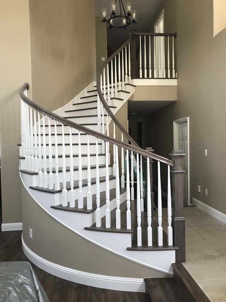 A curved staircase with white railings in a living room.
