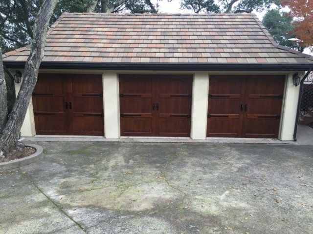 A garage with three wooden doors and a tiled roof
