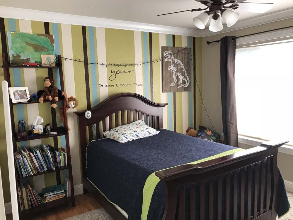 A bedroom with a bed , bookshelf , and ceiling fan.