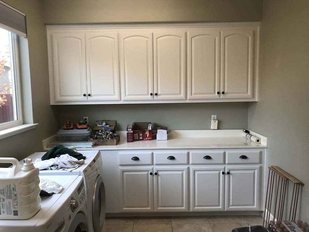 A laundry room with white cabinets , a washer and dryer , and a sink.
