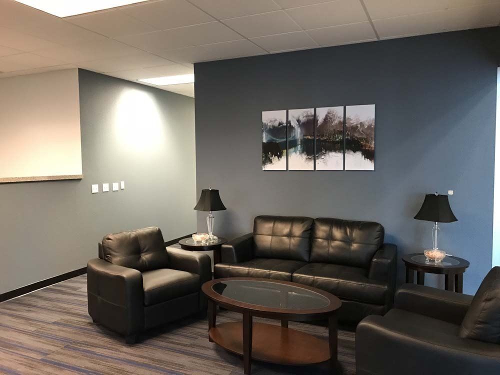 A living room with a couch , chairs , and a coffee table.