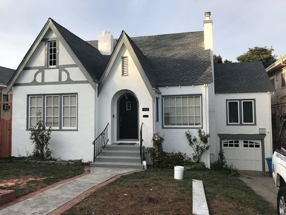 A white house with a gray roof and a black door