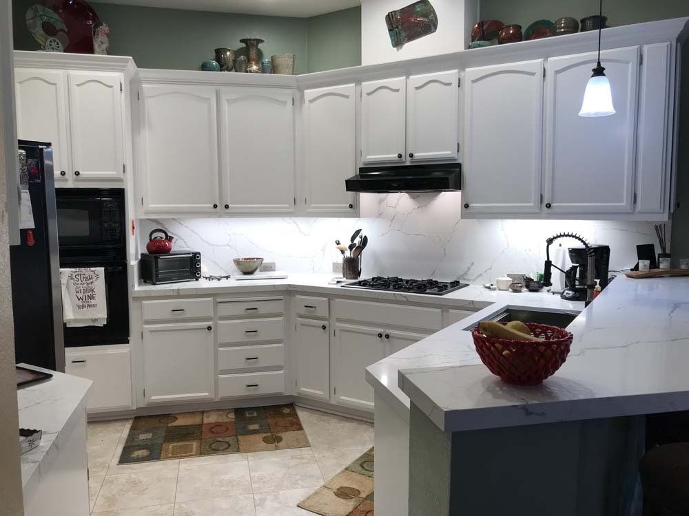 A kitchen with white cabinets and a bowl of fruit on the counter.