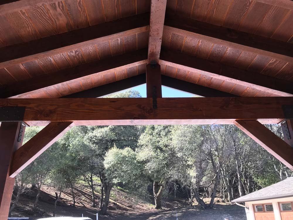 A wooden structure with a view of trees and a house in the background