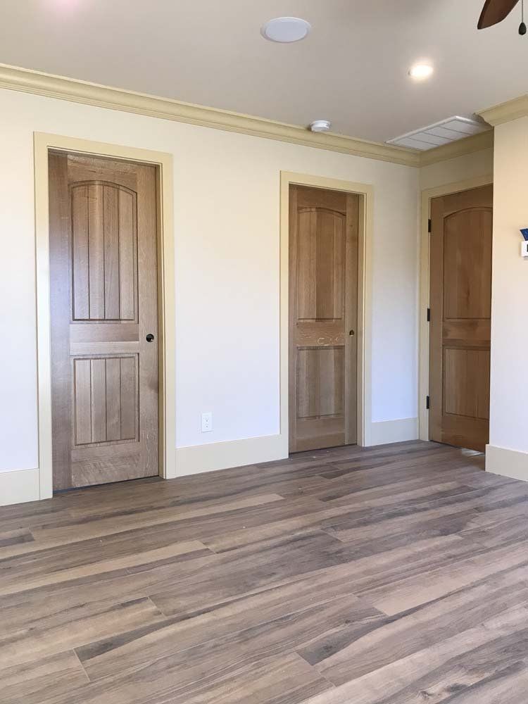 A room with hardwood floors and wooden doors and a ceiling fan.