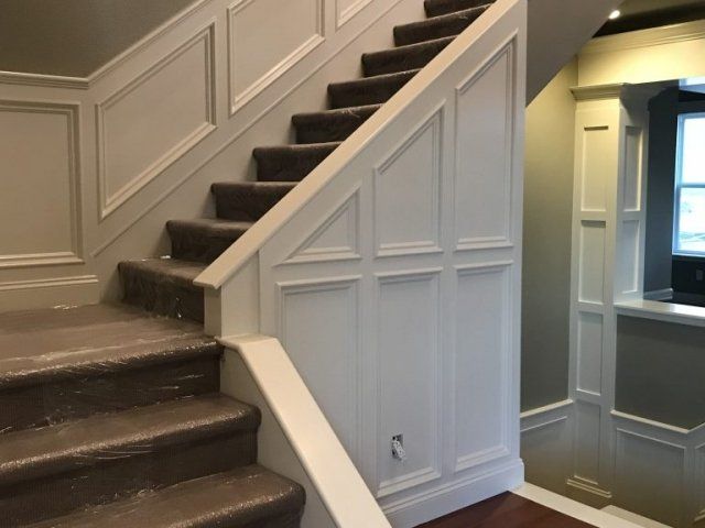 A staircase with a white railing and brown carpet