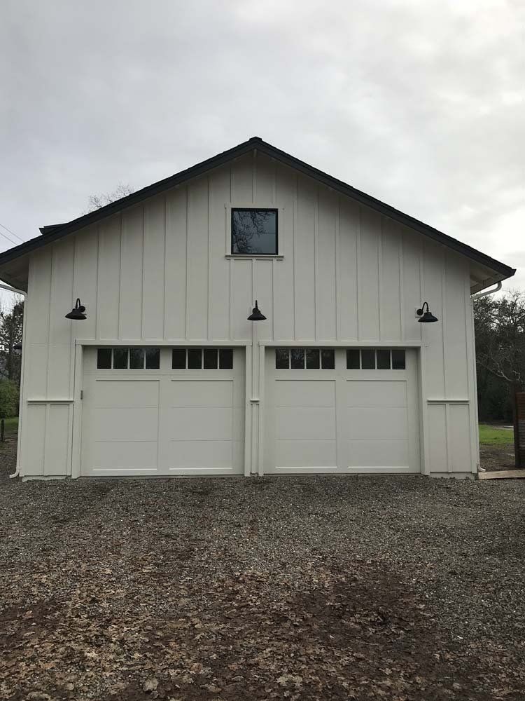 A white garage with two garage doors and a black roof.