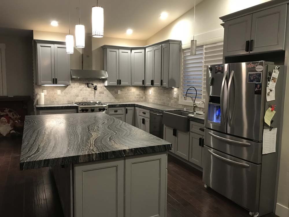 A kitchen with stainless steel appliances and gray cabinets.