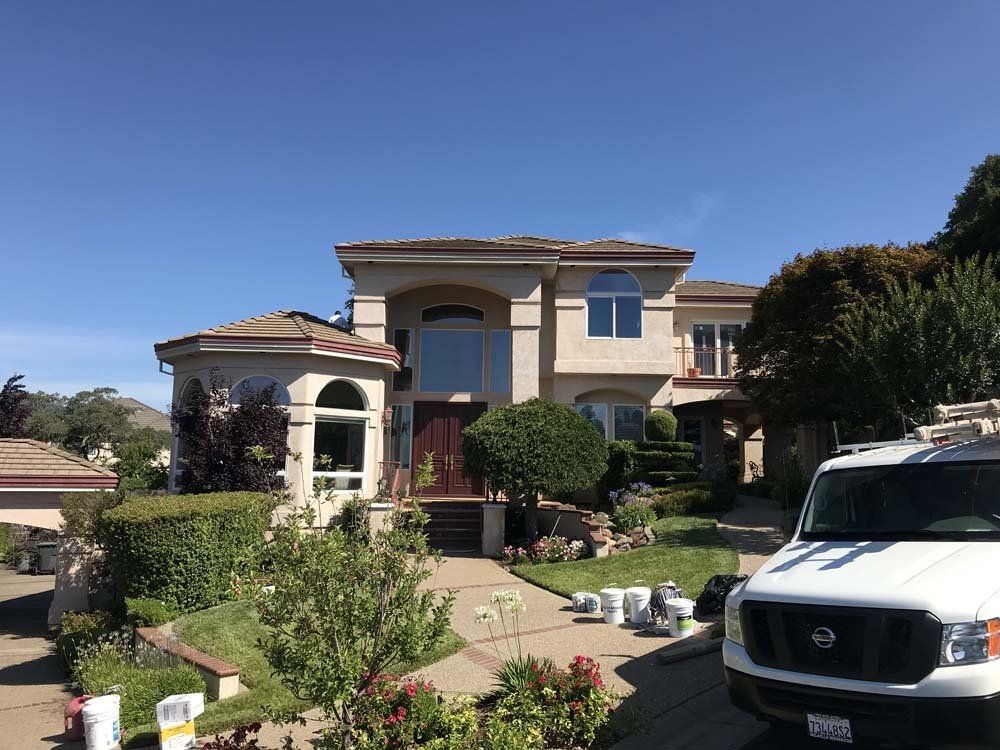 A white van is parked in front of a large house.